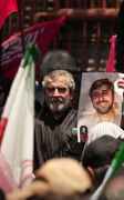 علی باقری با عکس برادر شهیدش در مراسم بدرقه پیکر مطهر امام شهید